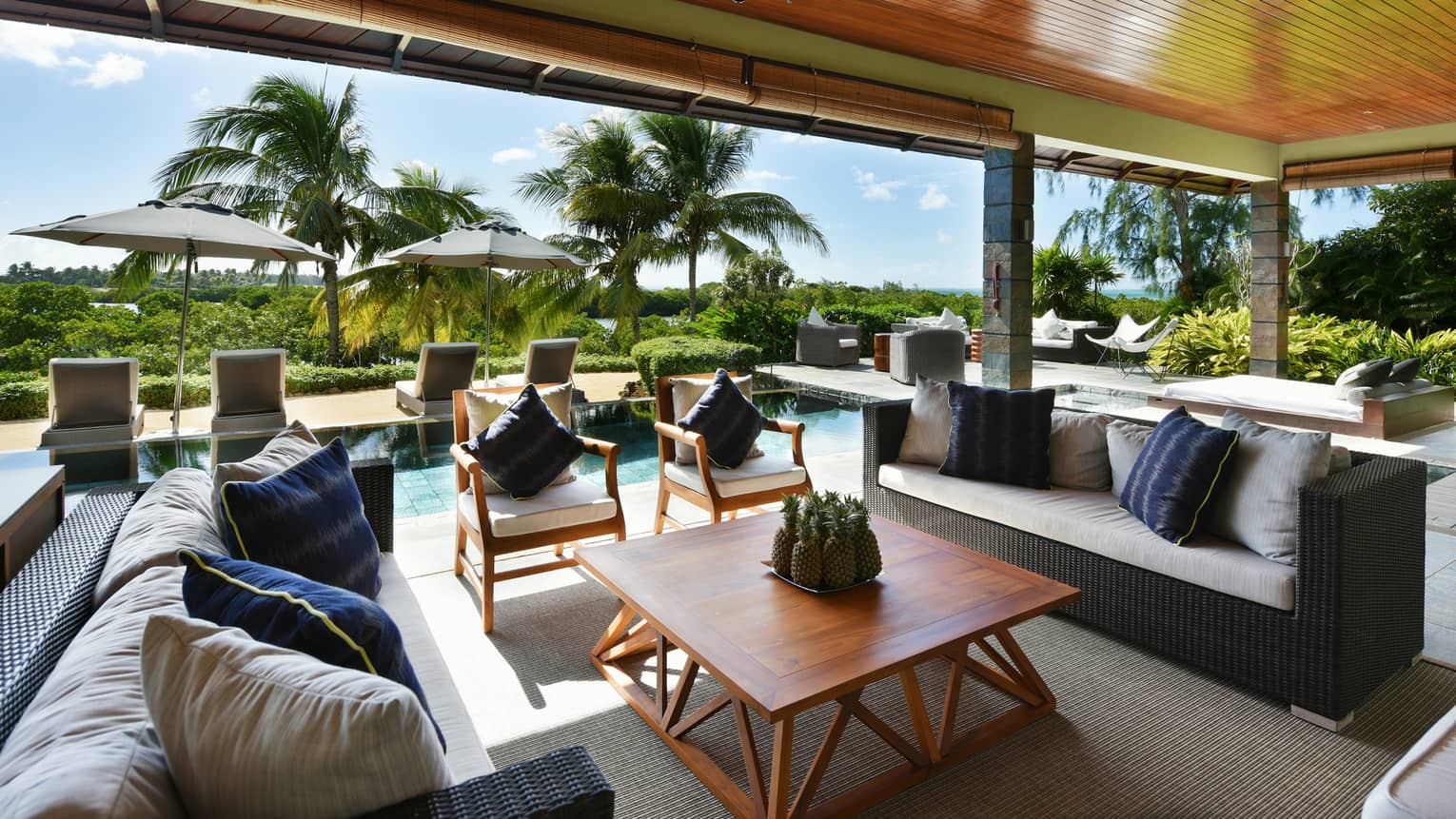 Grand Residence Villa long wicker sofas, wood furniture under wood roof, lounge chairs lining pool