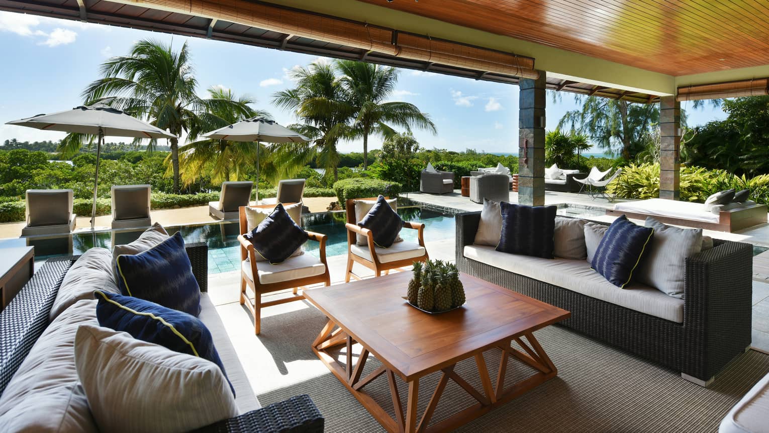 Grand Residence Villa long wicker sofas, wood furniture under wood roof, lounge chairs lining pool