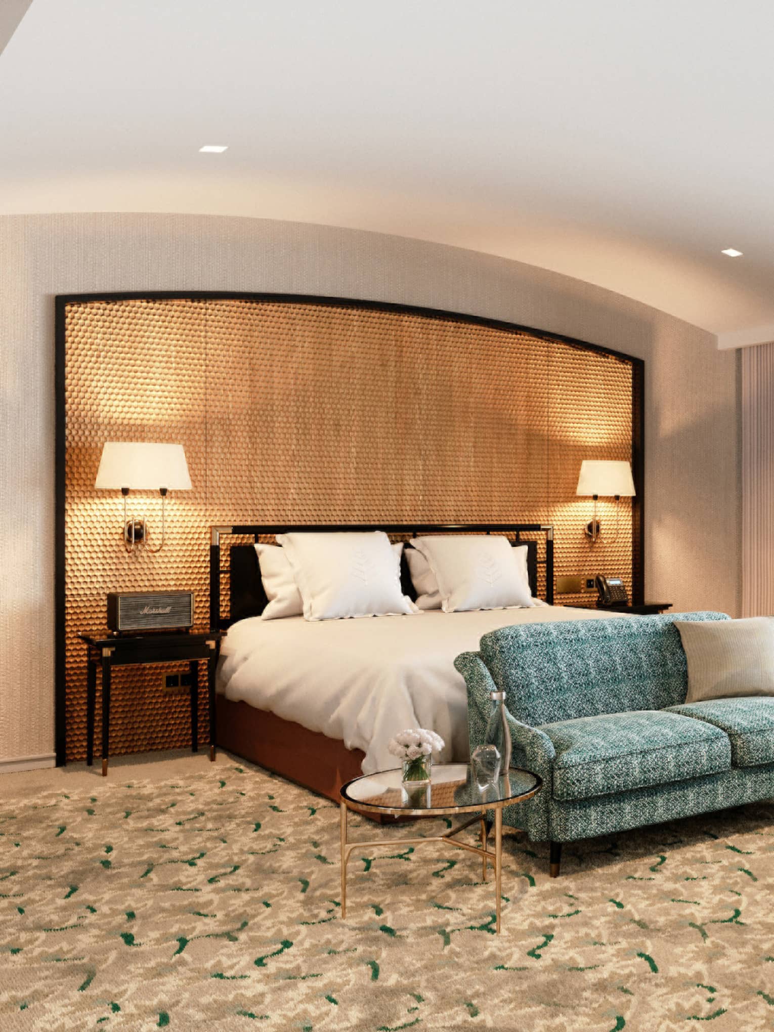 Spacious hotel room with a large bed, green patterned sofa, desk and large window with sheer curtains.