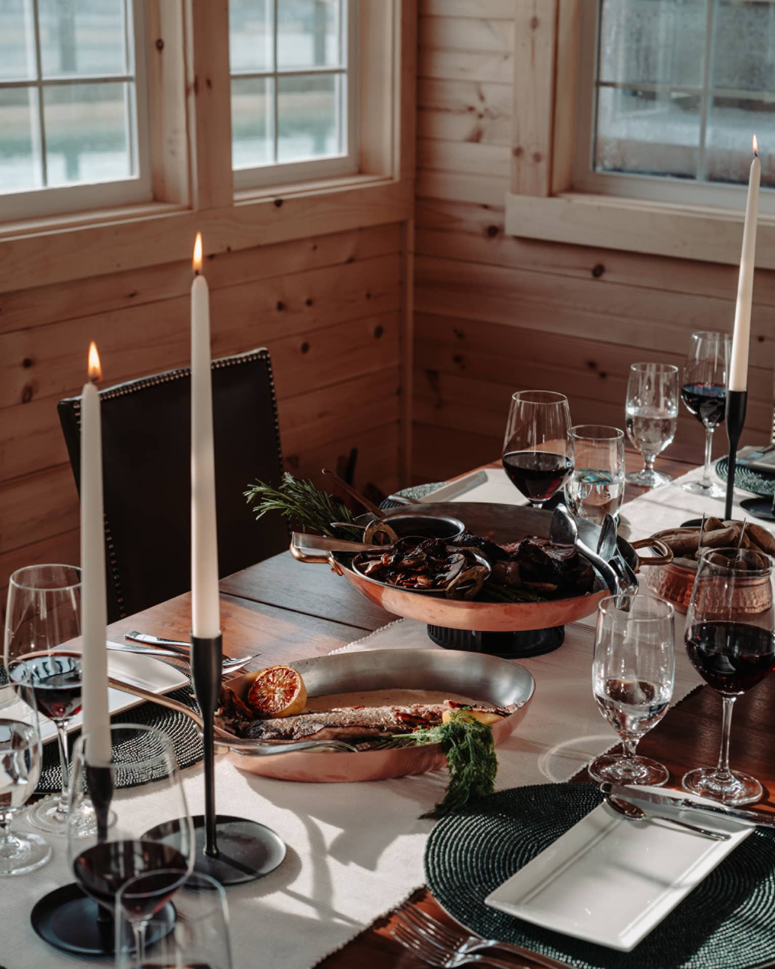Dining table set with plates, silverware, wine glasses and candles