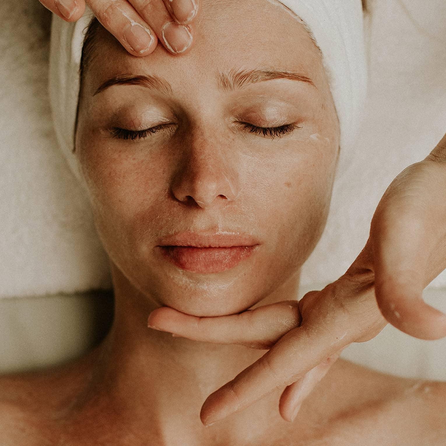 A woman reclines as a spa attendant performs a facial