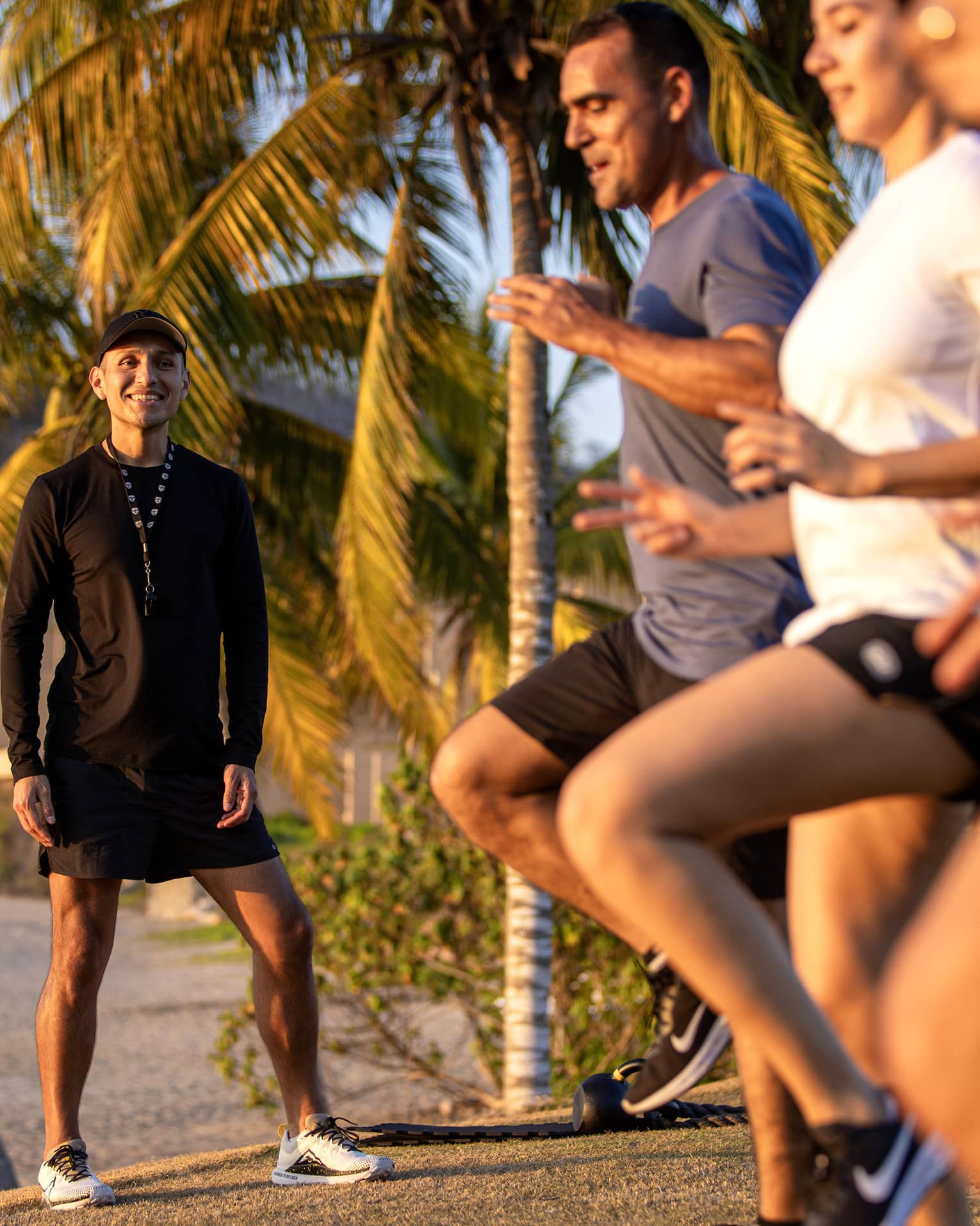 Fitness instructor leading an outdoor workout class with three guests.