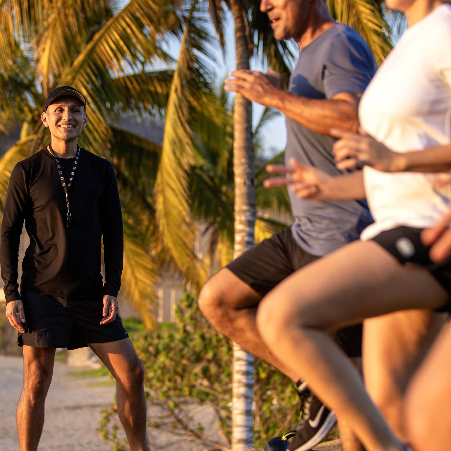 Fitness instructor leading an outdoor workout class with three guests.