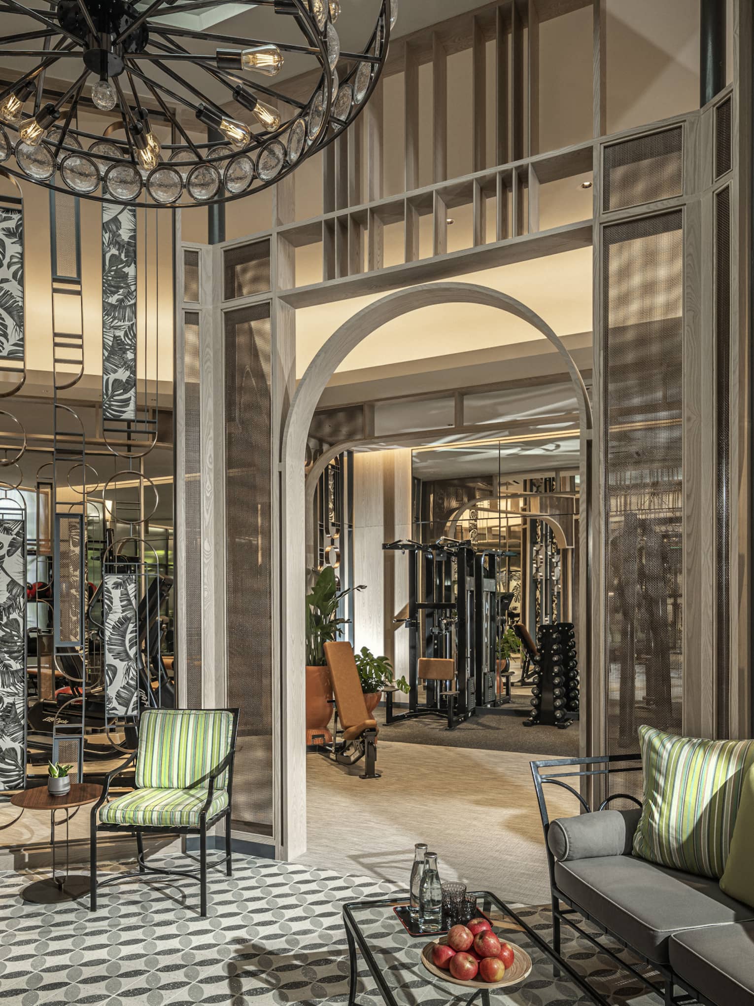 Fitness Centre lobby with high ceilings, round wrought-iron chandelier, sofa with green accent pillows