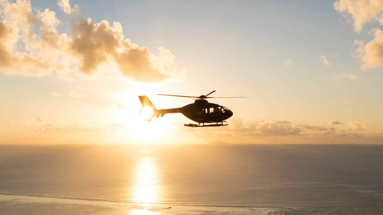 Helicopter over the sea at sunset
