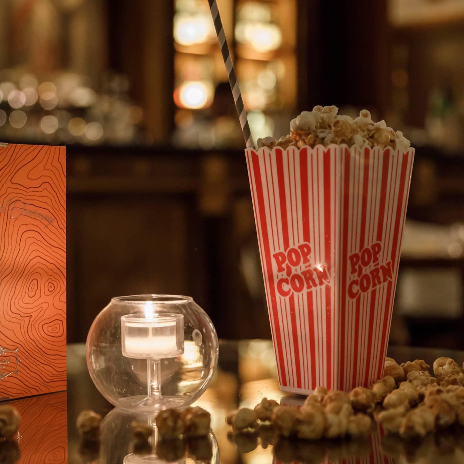 Warmly lit table with movie popcorn and tealight candle.