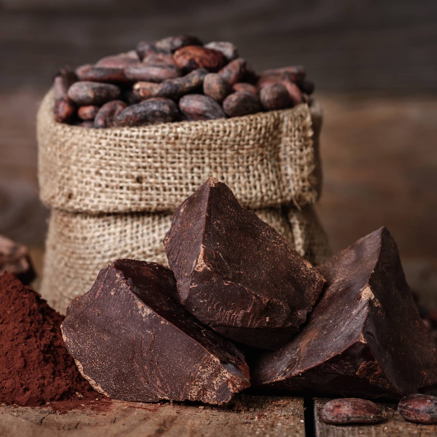 Chunks of chocolate, cocoa powder and coffee beans in a burlap sack