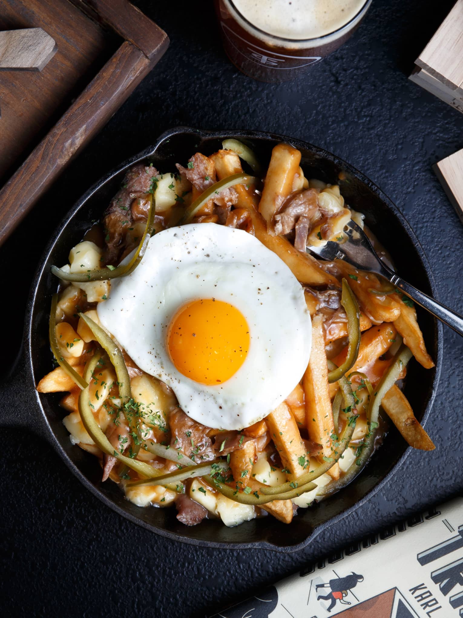A skillet filled with fries, various spices and a fried egg.