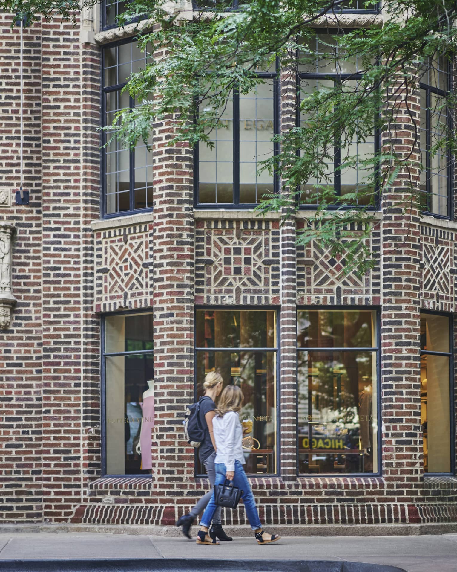 Two people walking down a street with brick buildings.
