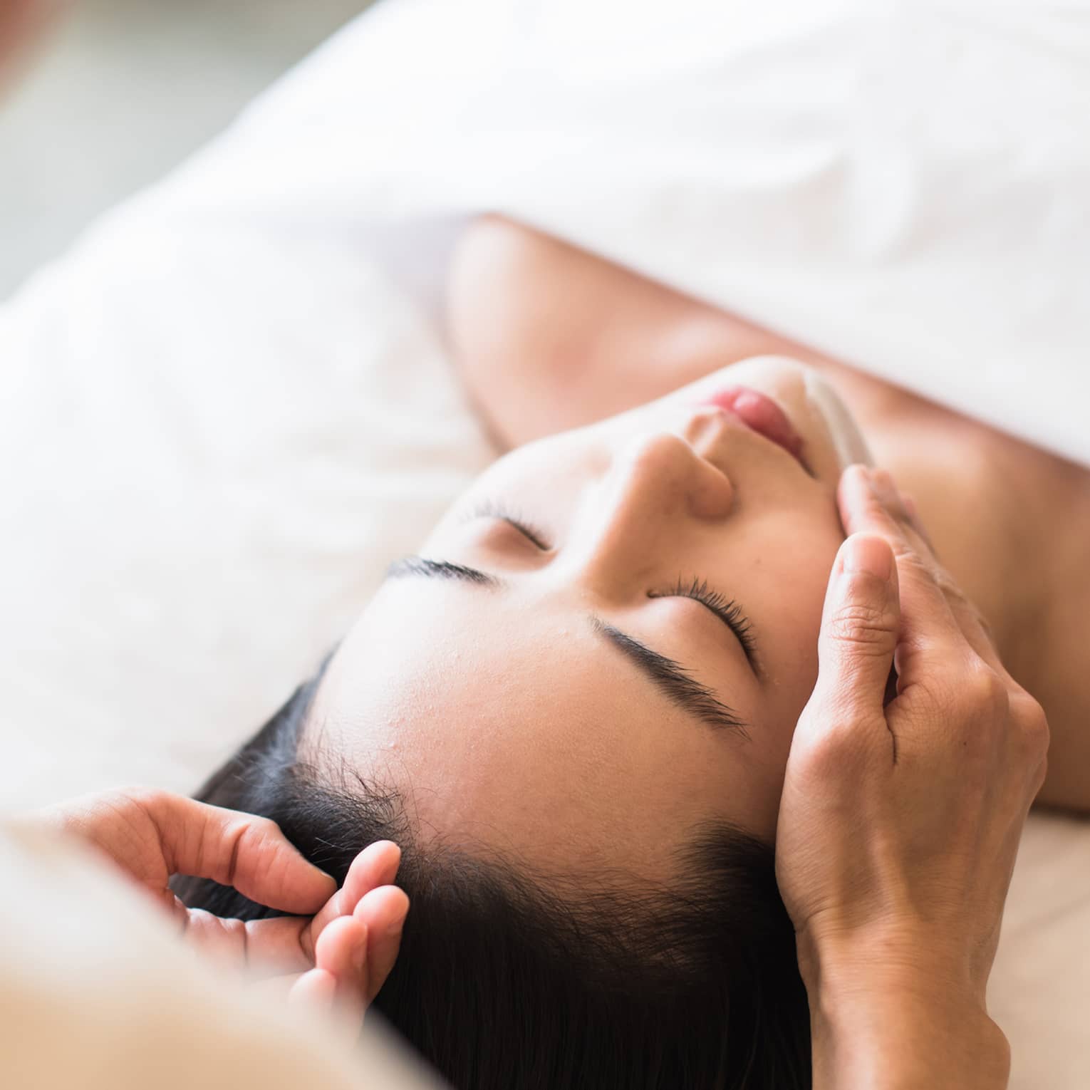 A guest receiving a soothing facial at a spa, lying on a massage table, surrounded by calming décor and soft lighting.