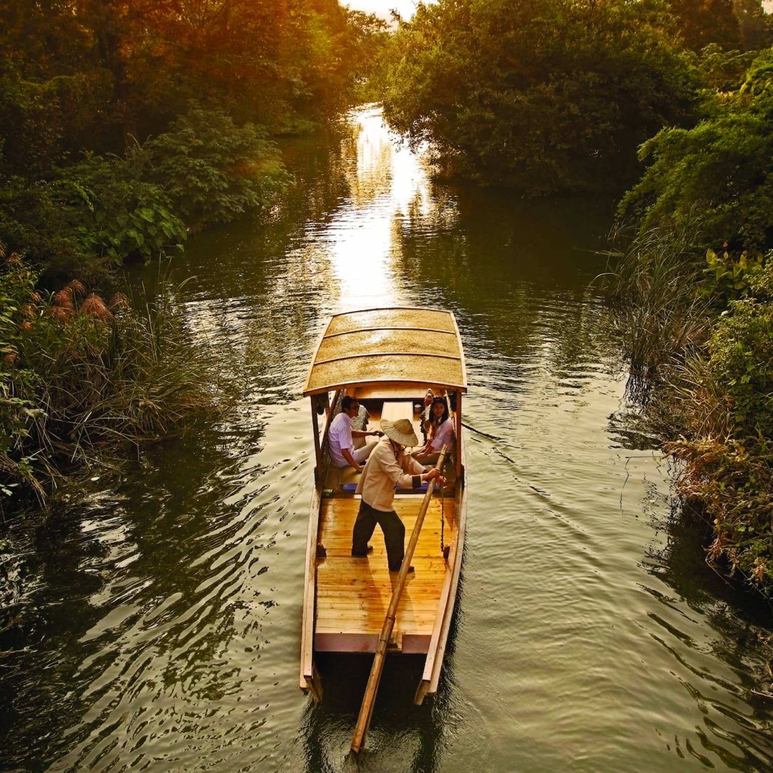 Traditional Chinese wooden boat sails down river in Xixi Wetland National Park