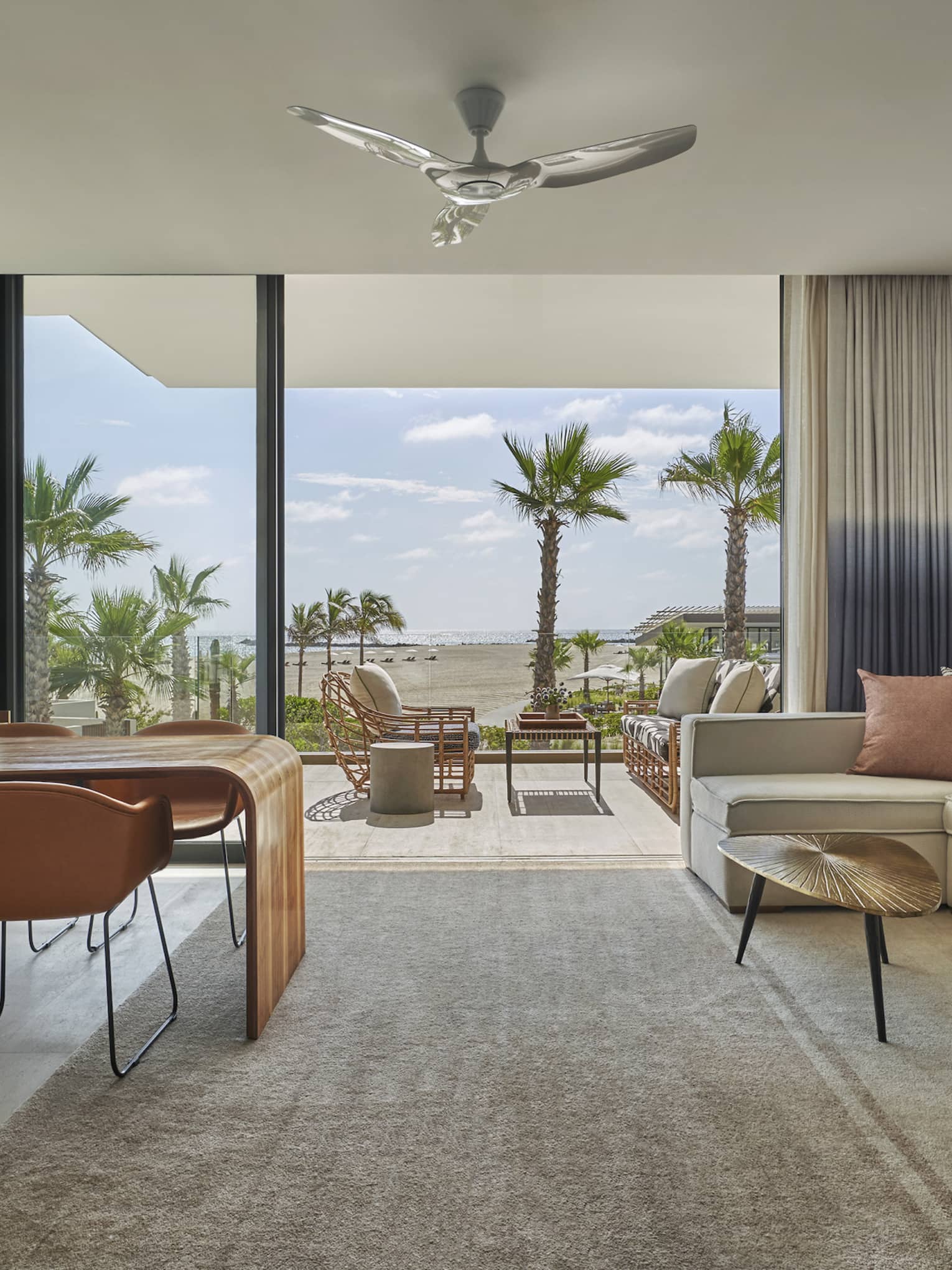 Living room with dining table for four, cream-coloured l-shaped sofa, walk-out balcony