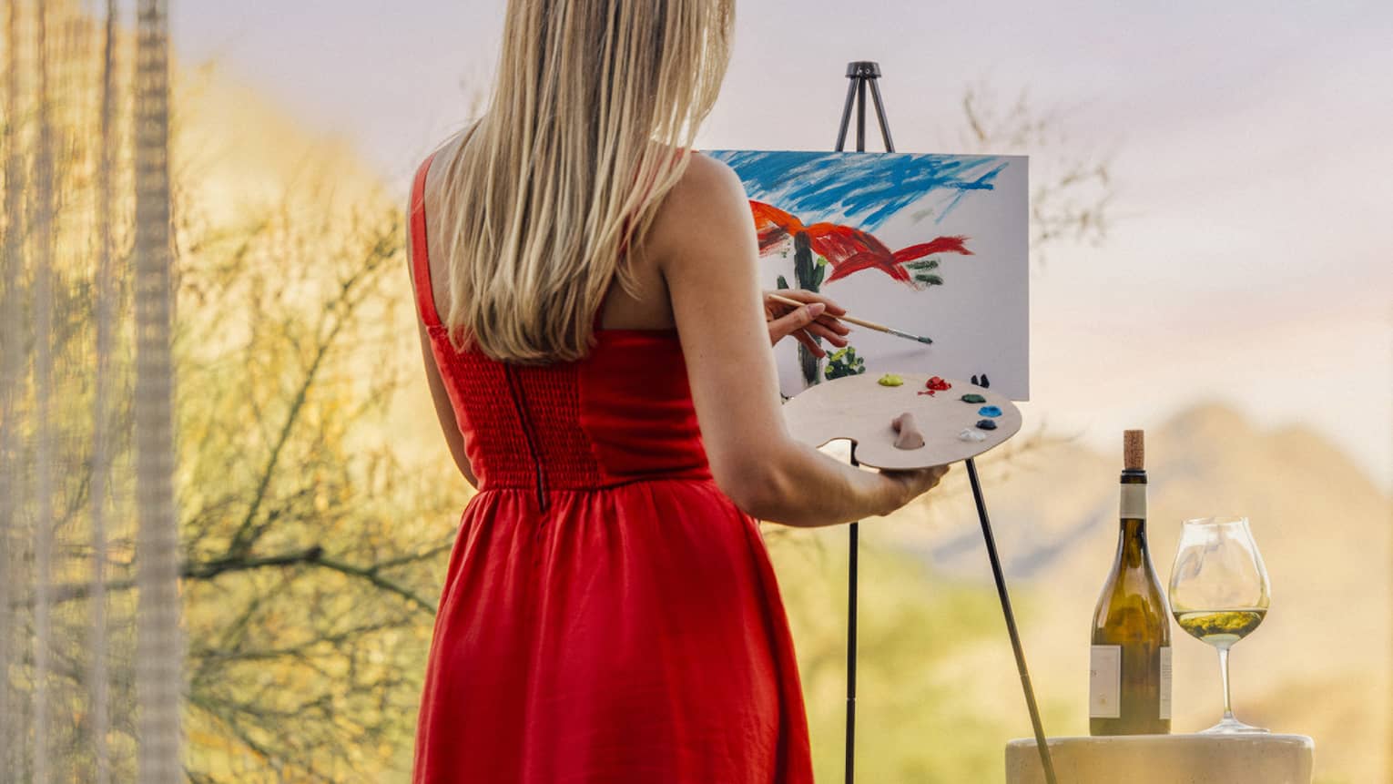 Person wearing a red dress and painting with a wine glass beside them.