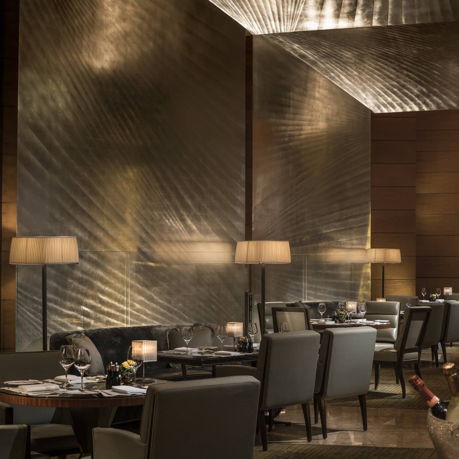 Elegant restaurant dining area with softly lit tables, upholstered chairs, and ambient lighting, set for a formal dinner service.