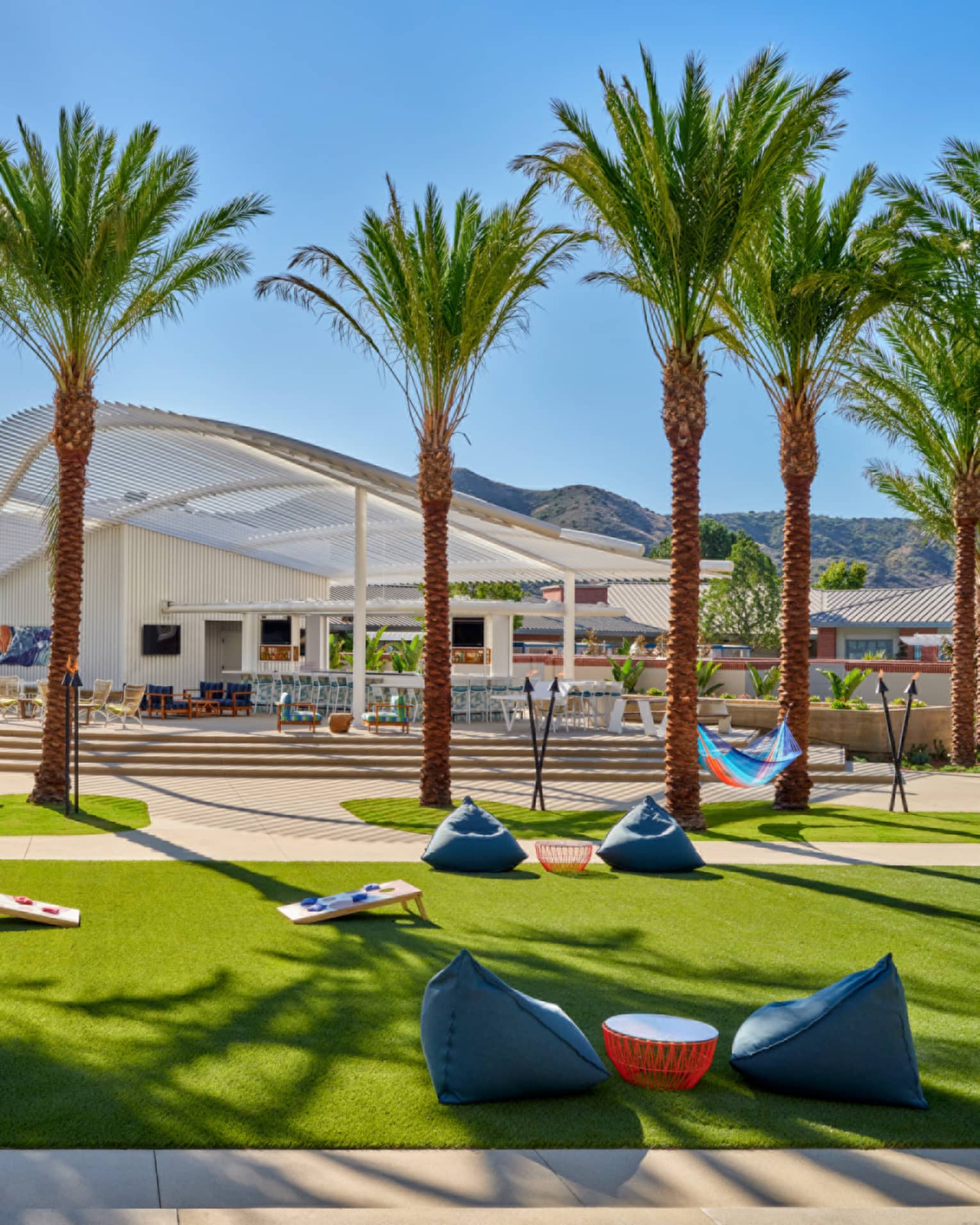 An outdoor sitting area with beanbag chairs and palm trees.