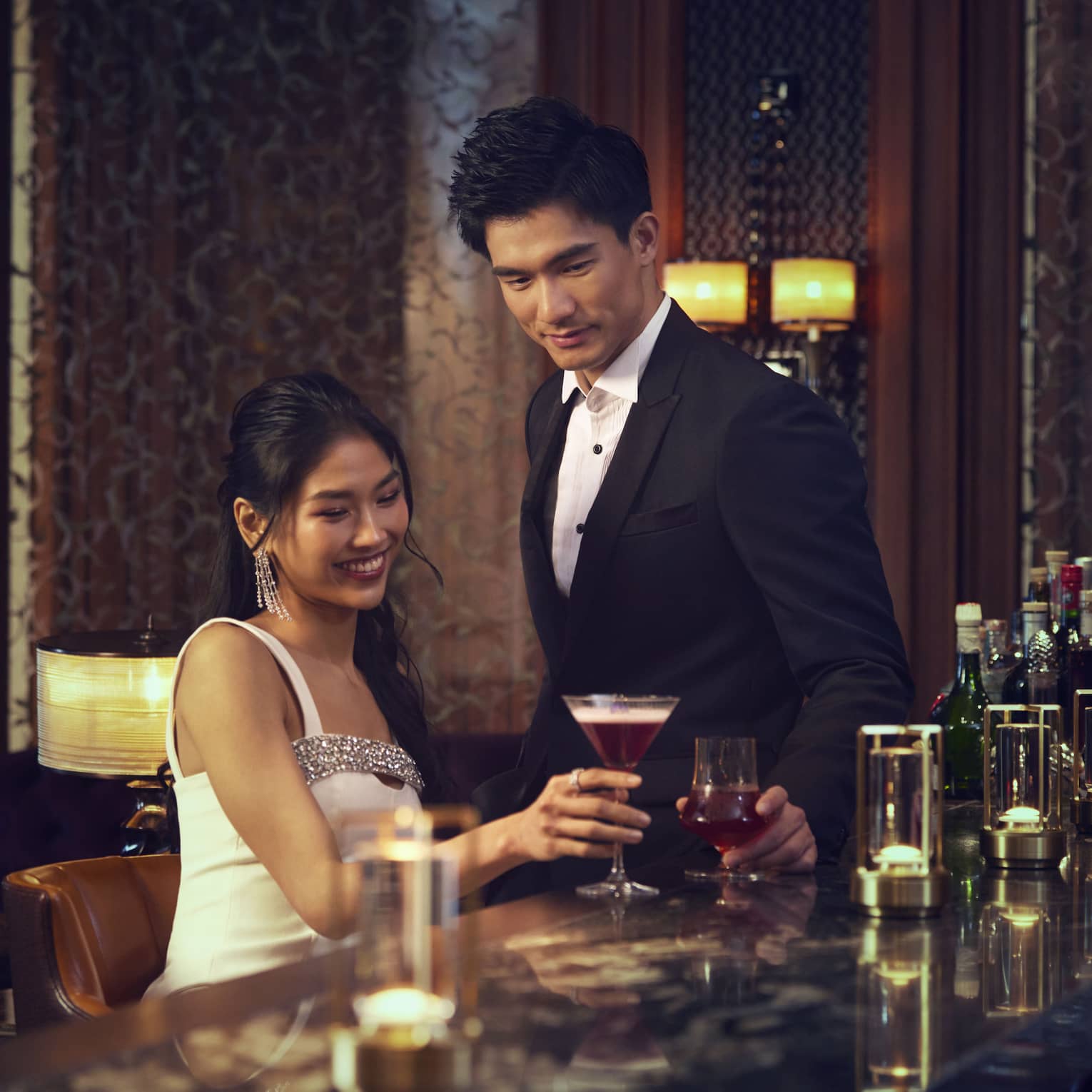 Man and woman cheers with cocktails at luxury hotel bar