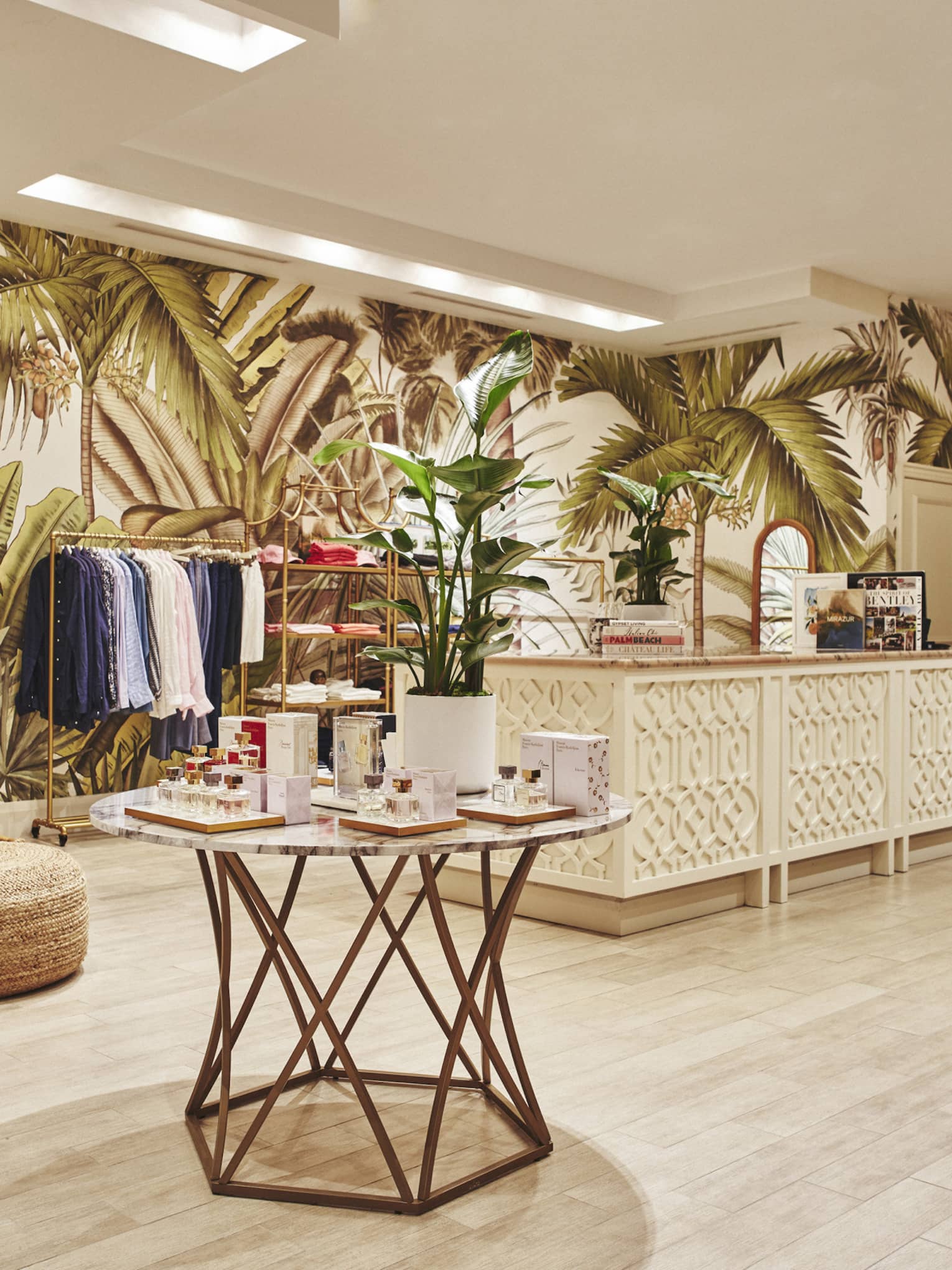 A brightly lit store with light wood features and clothes on shelves and hangers.