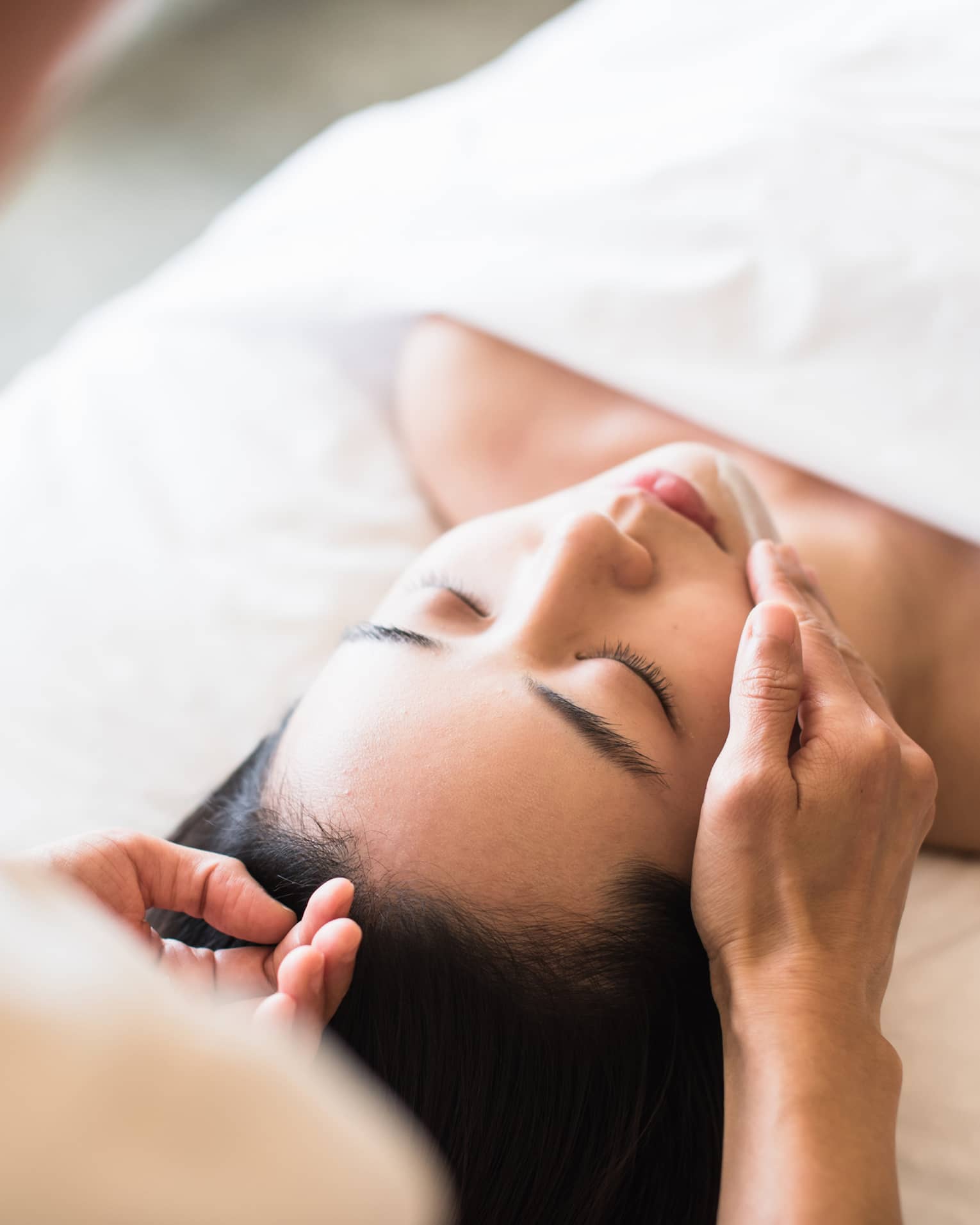 A guest receiving a soothing facial at a spa, lying on a massage table, surrounded by calming décor and soft lighting.