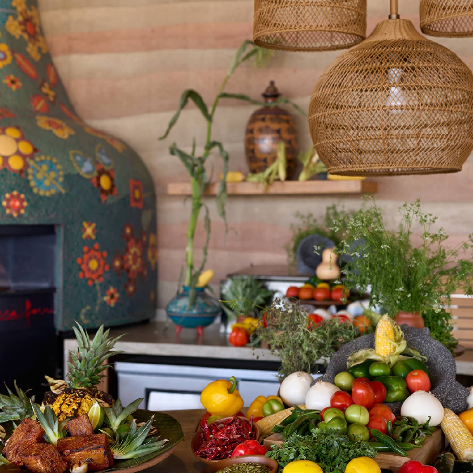 A kitchen with colourful mosaic wood-burning oven, and fresh fruit and vegetables on the table