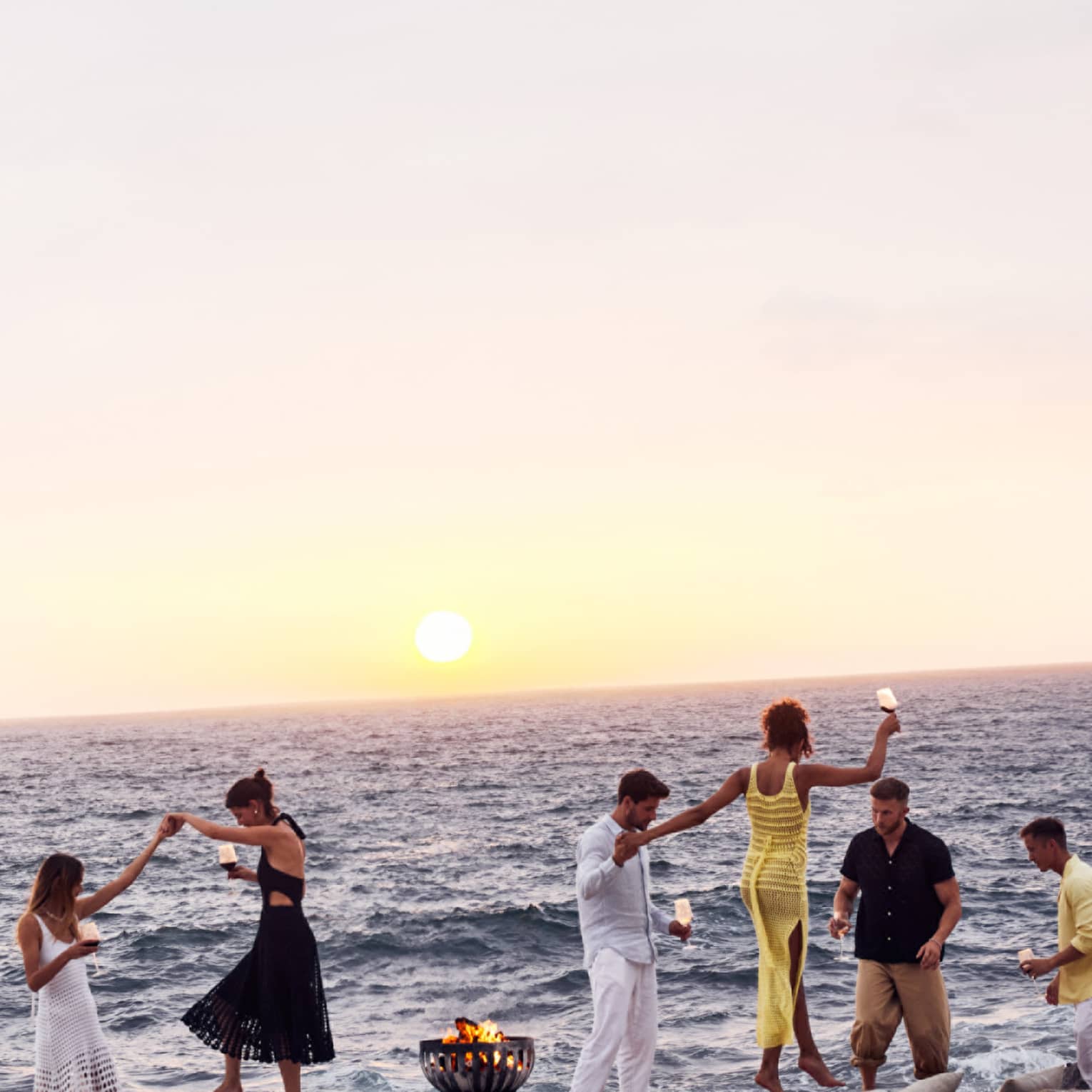 A group of people dancing on a beach.