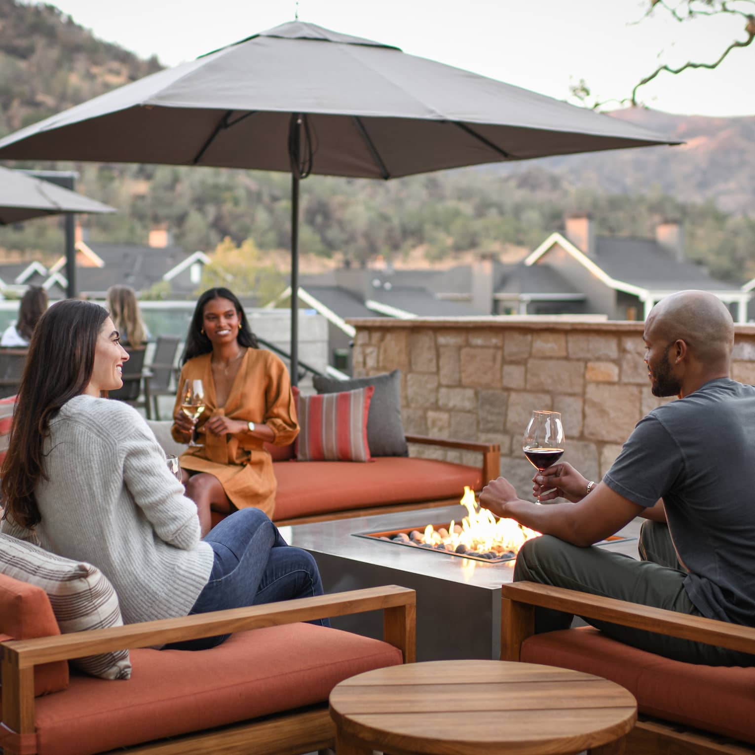A group of people sitting outside with glasses of wine.
