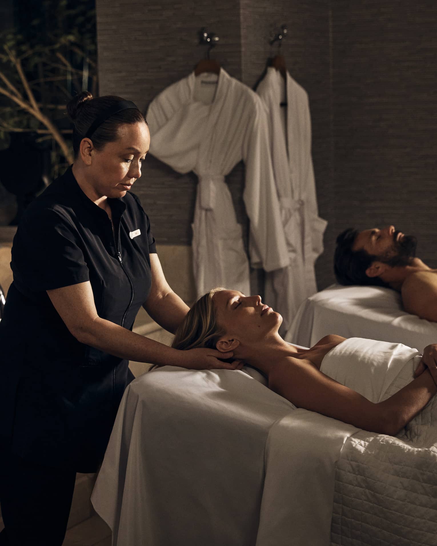 Two guests laying on massage tables in a room with a spa tub.