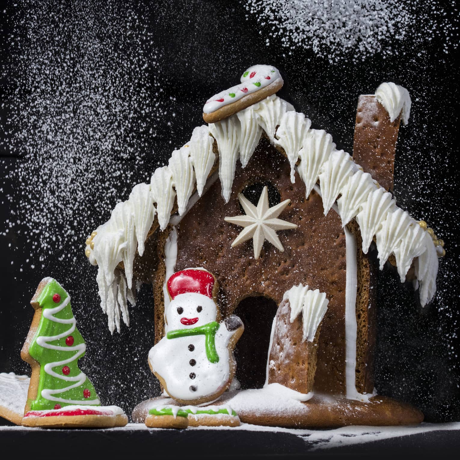 Gingerbread house being dusted with powdered sugar that looks like snow,Gingerbread house being dusted with powdered sugar that looks like snow