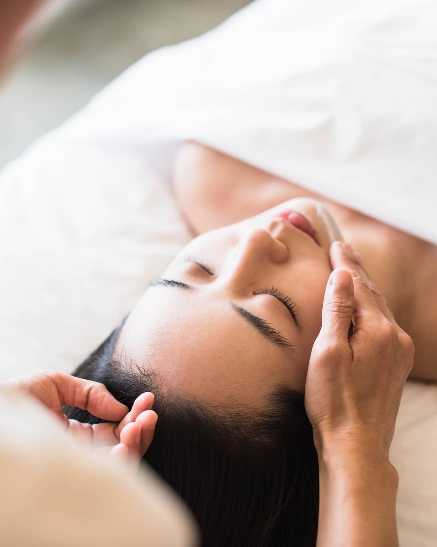 A guest receiving a soothing facial at a spa, lying on a massage table, surrounded by calming décor and soft lighting.