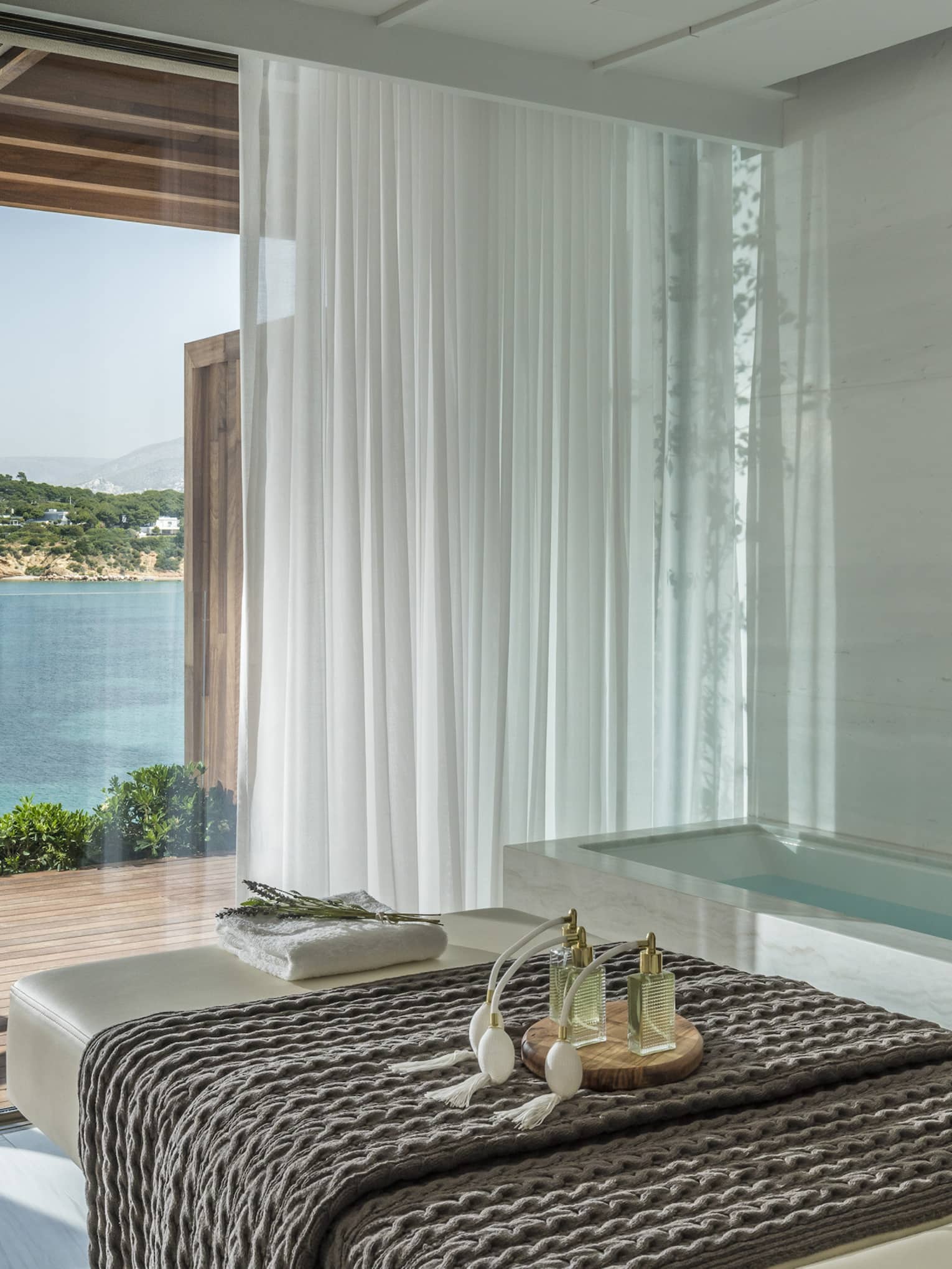 White spa table with dark blanket and water view from tall windows