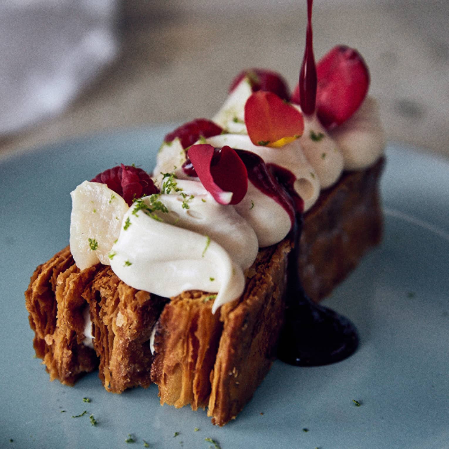 Dessert topped with cream and burgundy flower petals
