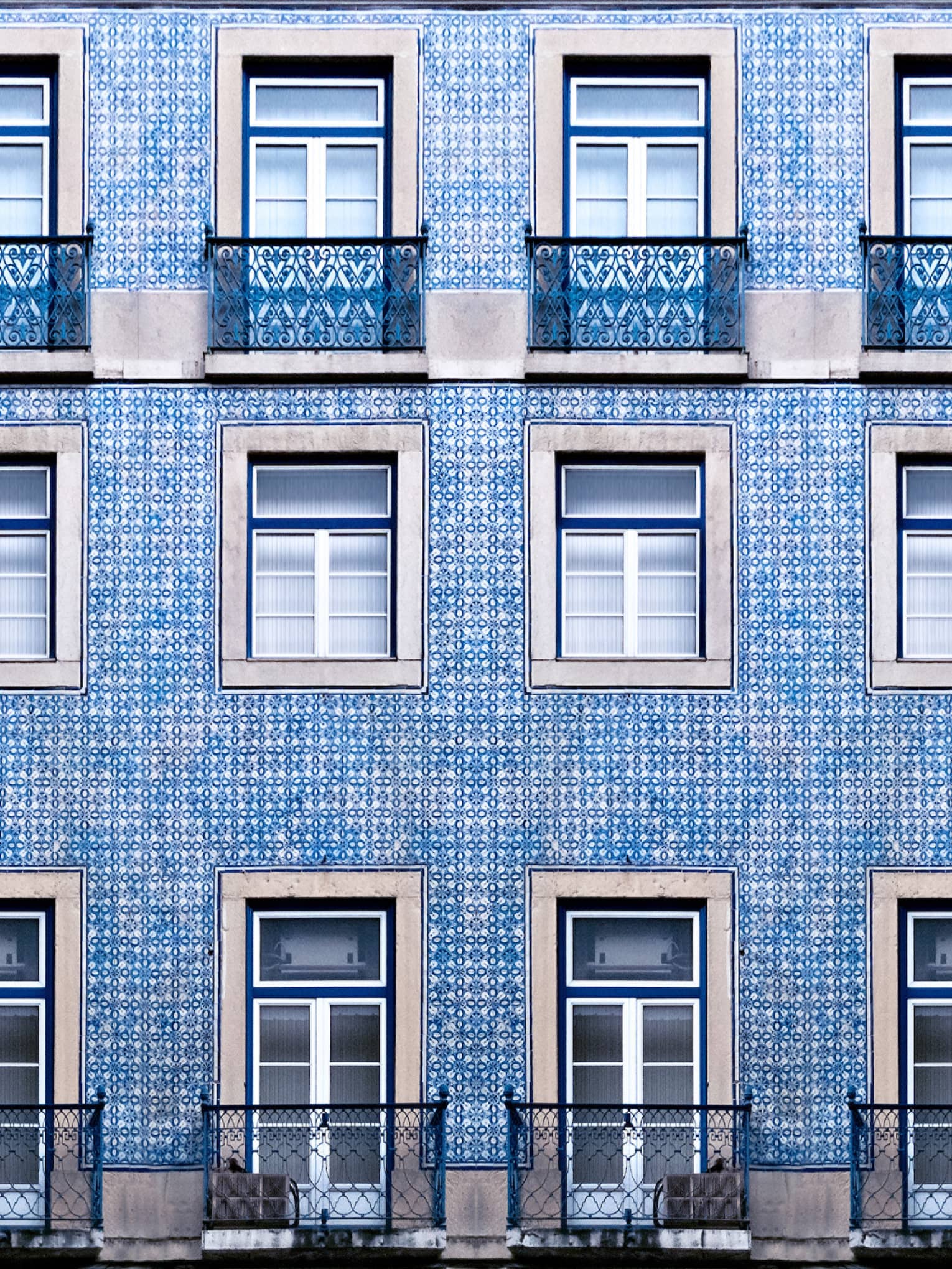 A blue tiled wall with many windows and balconies.