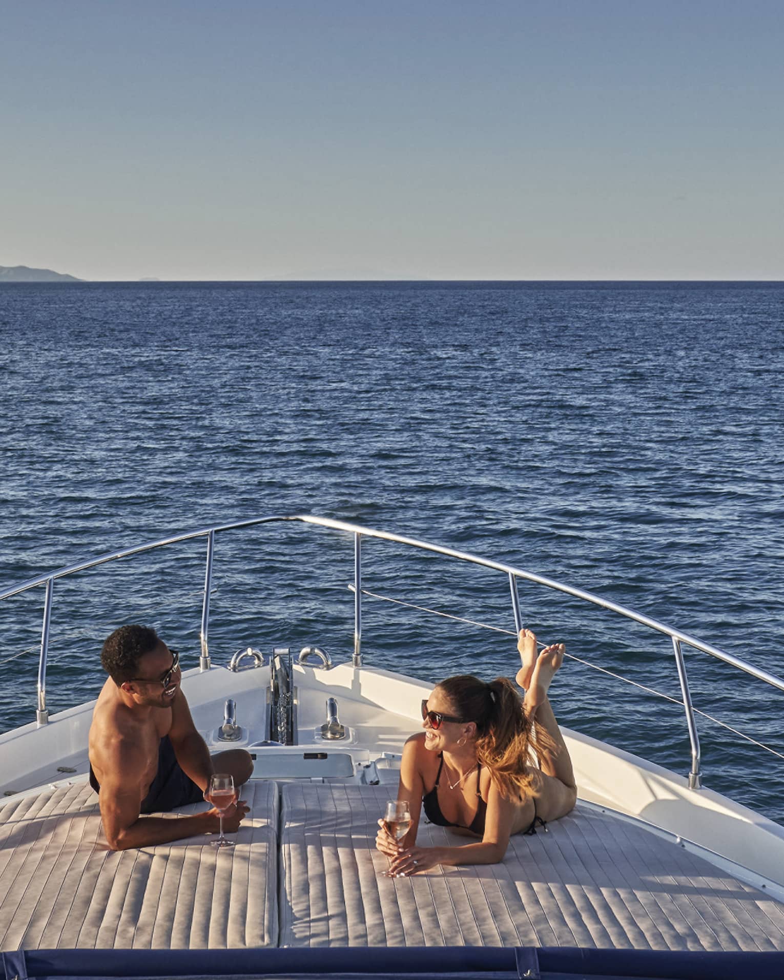 Man and woman lay on front of yacht