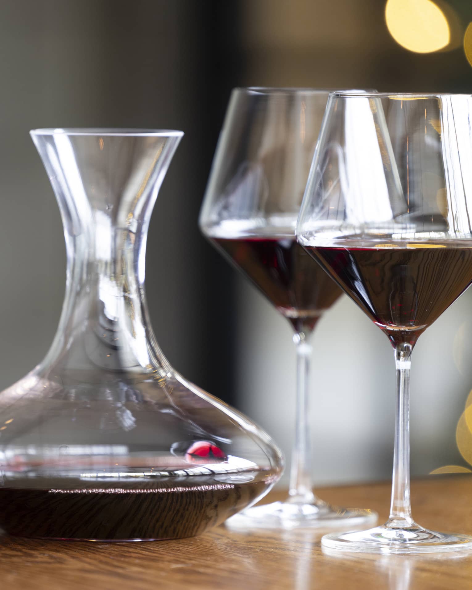 Two wine glasses on a table beside a wine pitcher