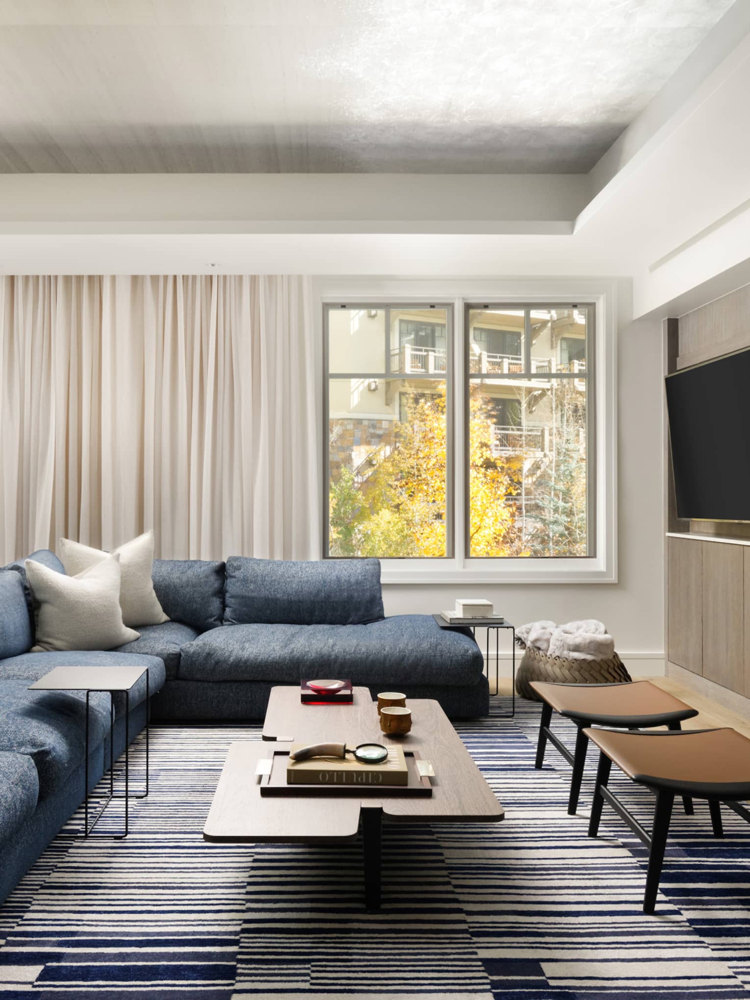 Living room with large blue sectional sofa, modern wooden coffee table, windows