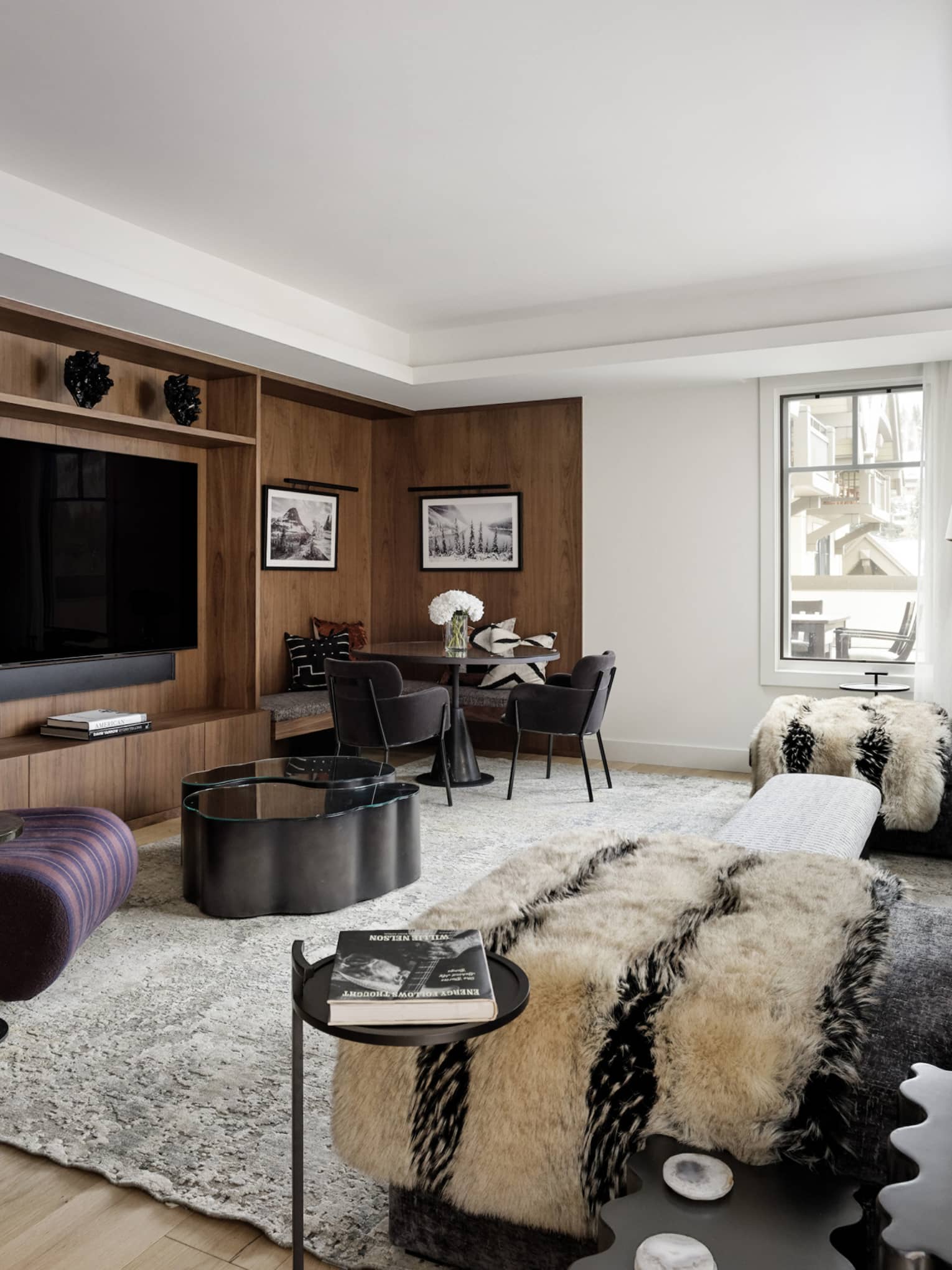 Contemporary living room of a private residence rental, featuring a grey sofa, plum-coloured arm chair and built-in media centre
