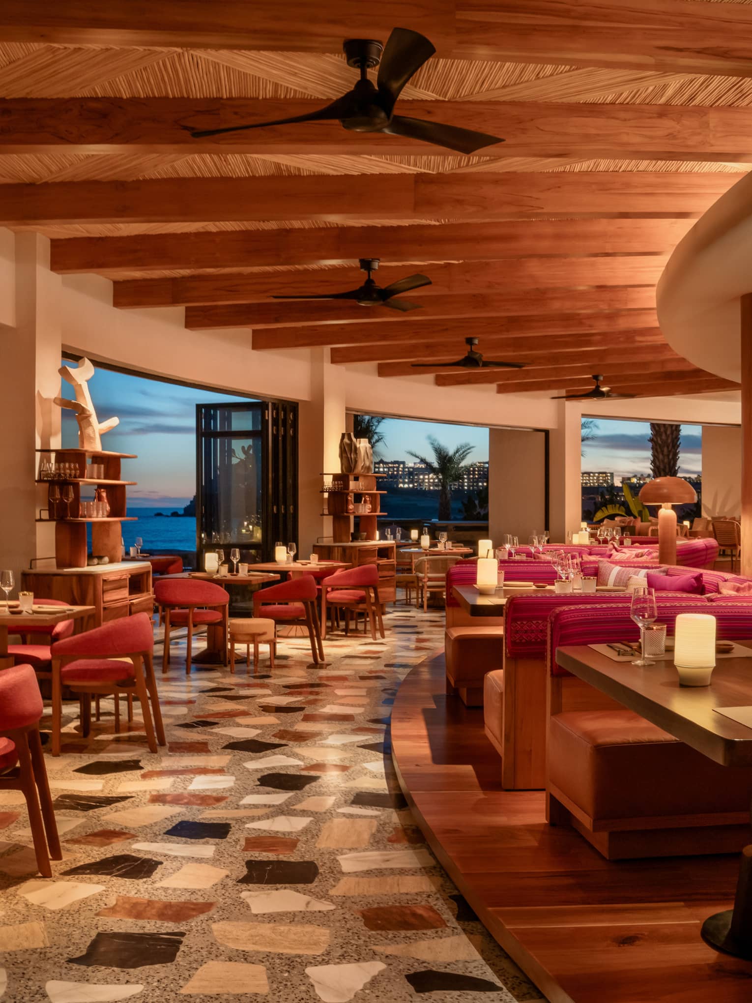 Interior, curved edge of resort restaurant with indoor-outdoor seating and ocean view