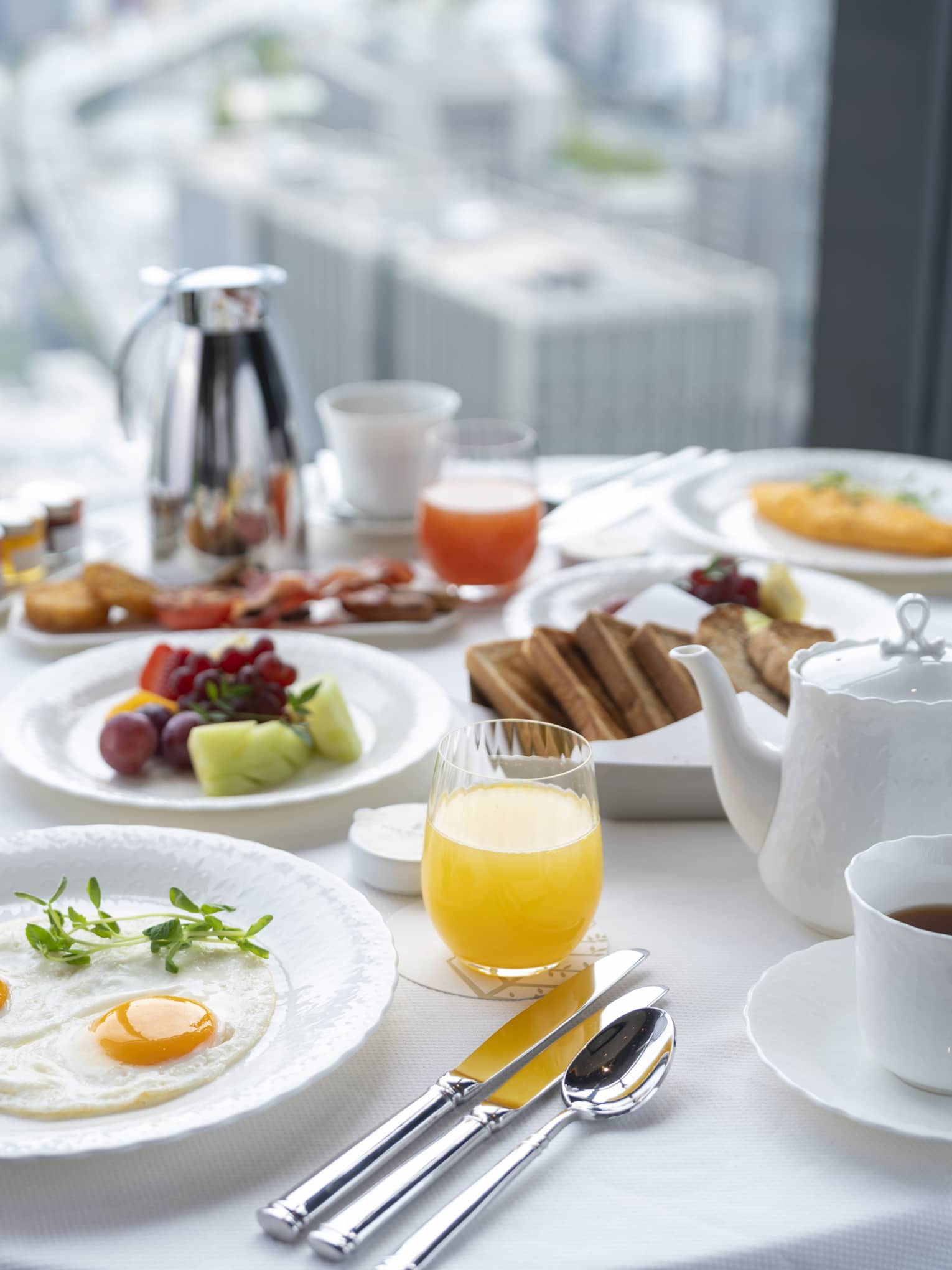 Luxurious in-room breakfast at Four Seasons Hotel Osaka with city views, eggs, fruit, and coffee.