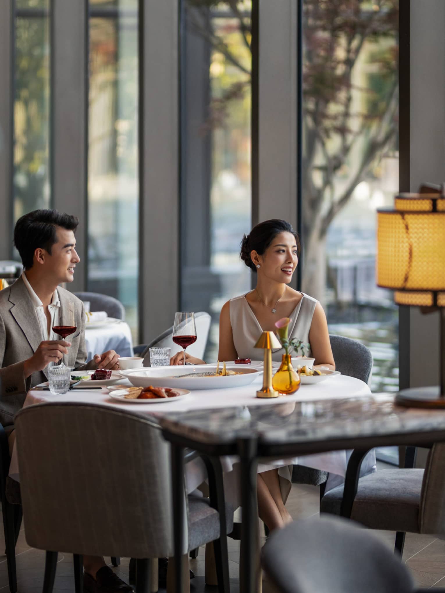 Man and woman dine at fine dining Chinese restaurant by the window with a pool view