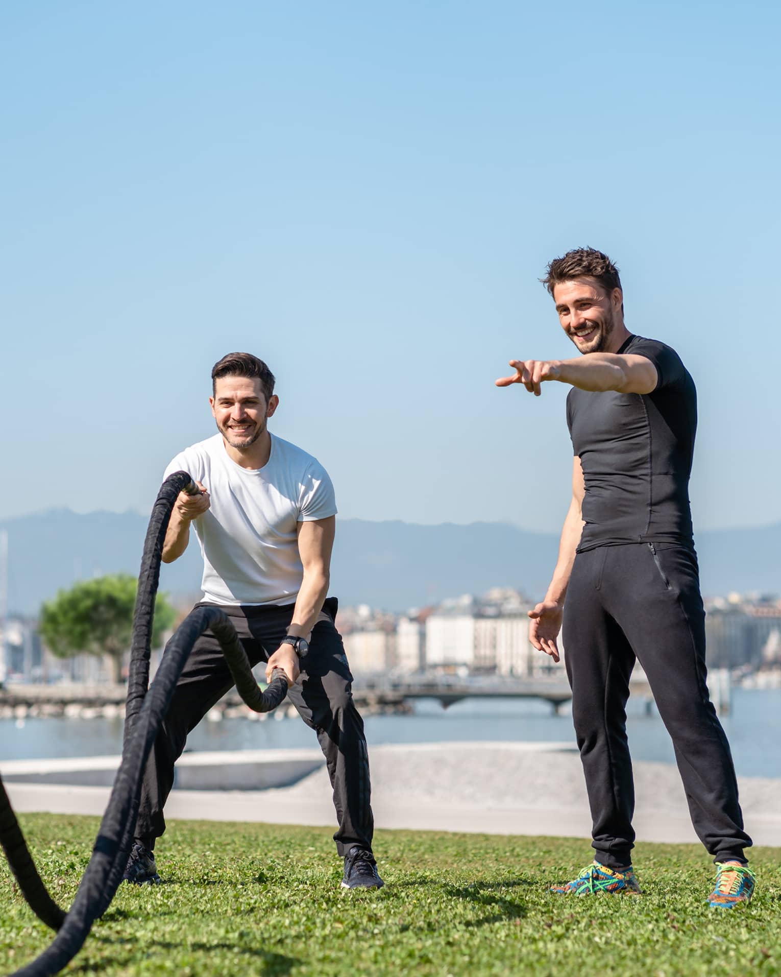 Man working out with ropes with guidance of trainer at Lake Geneva grassy shore