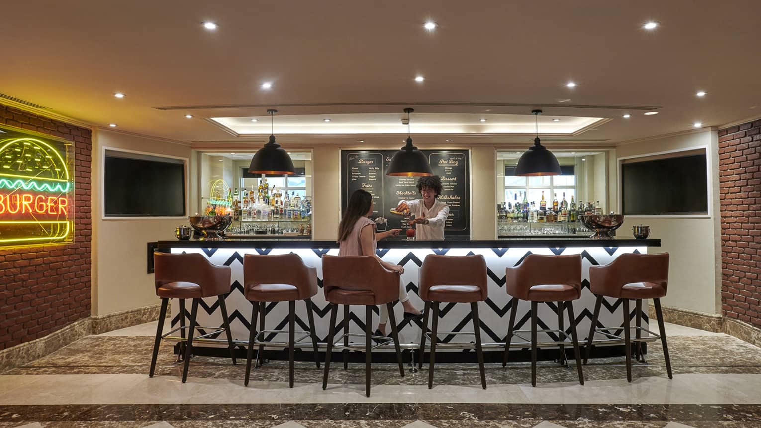 Bartender serves a woman a cocktail at Char Bar