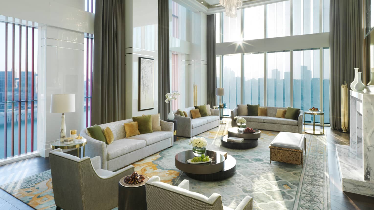 Royal Suite with high dome ceiling, modern crystal chandelier, sunny living room with several sofas and chairs, area rug