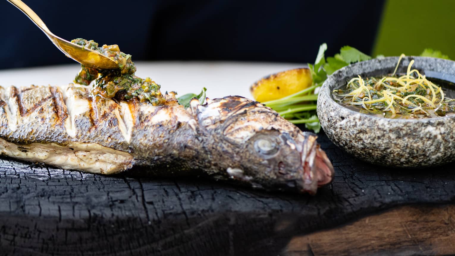 Grilled fish on a black tray.