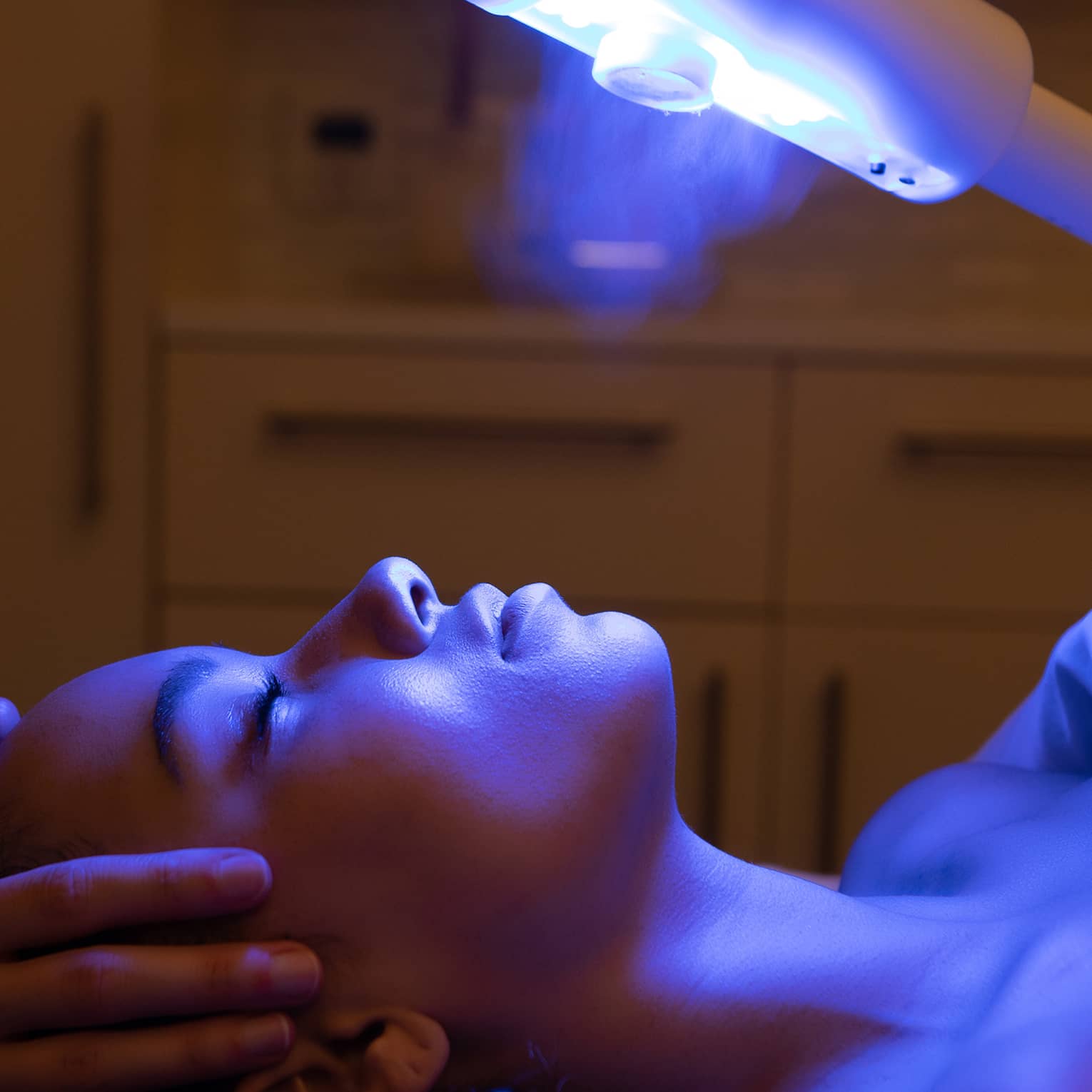 A guest laying on a spa table and receiving a light therapy treatment 