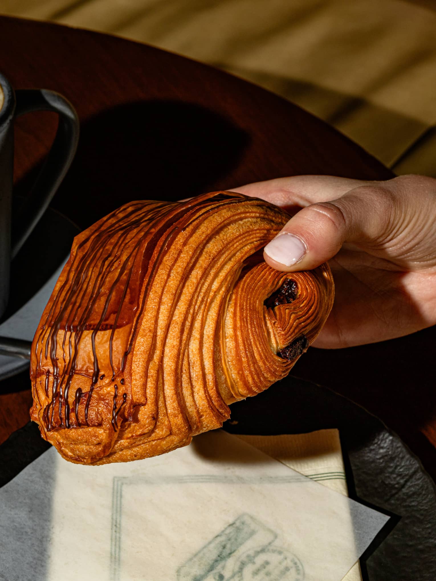 A croissant with a mug of coffee and a spoon