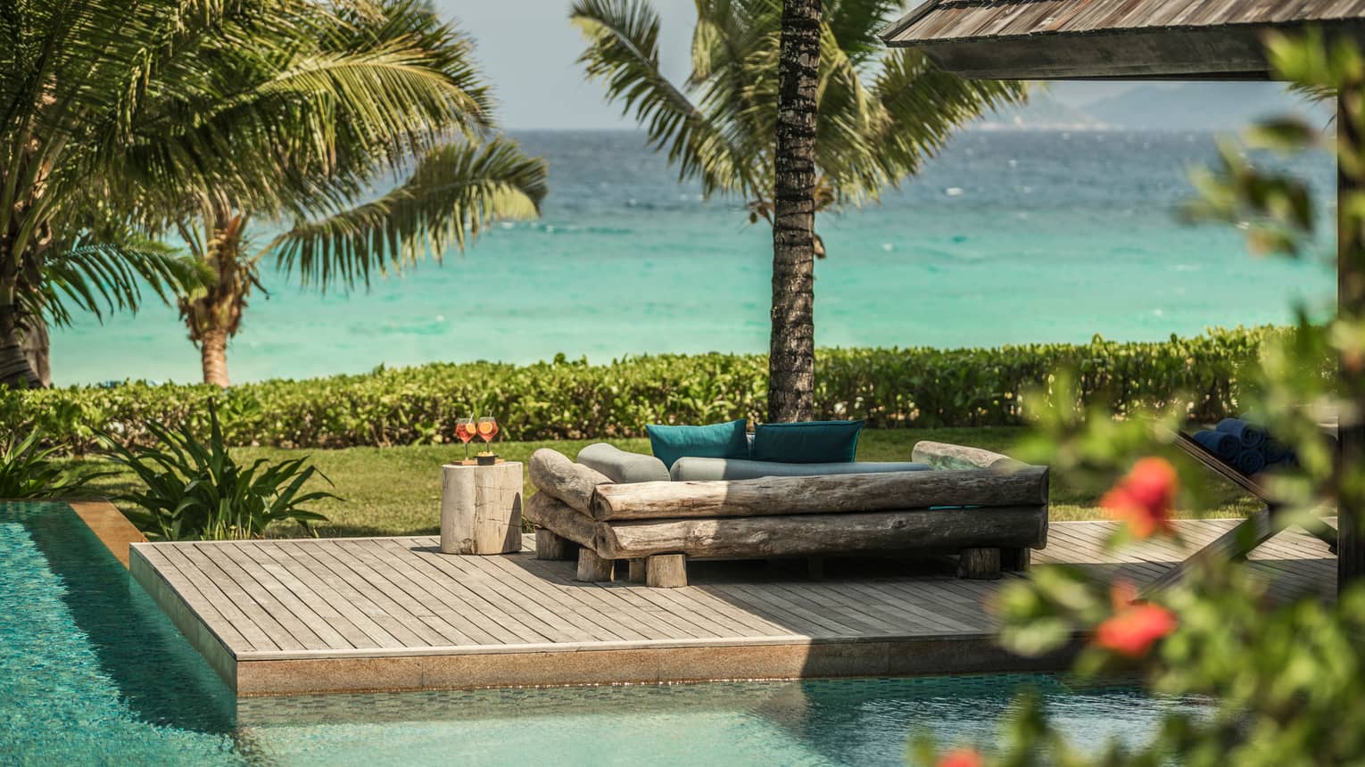 Kannel Bar swimming pool, wood deck, log loveseat looking out at palm trees, ocean