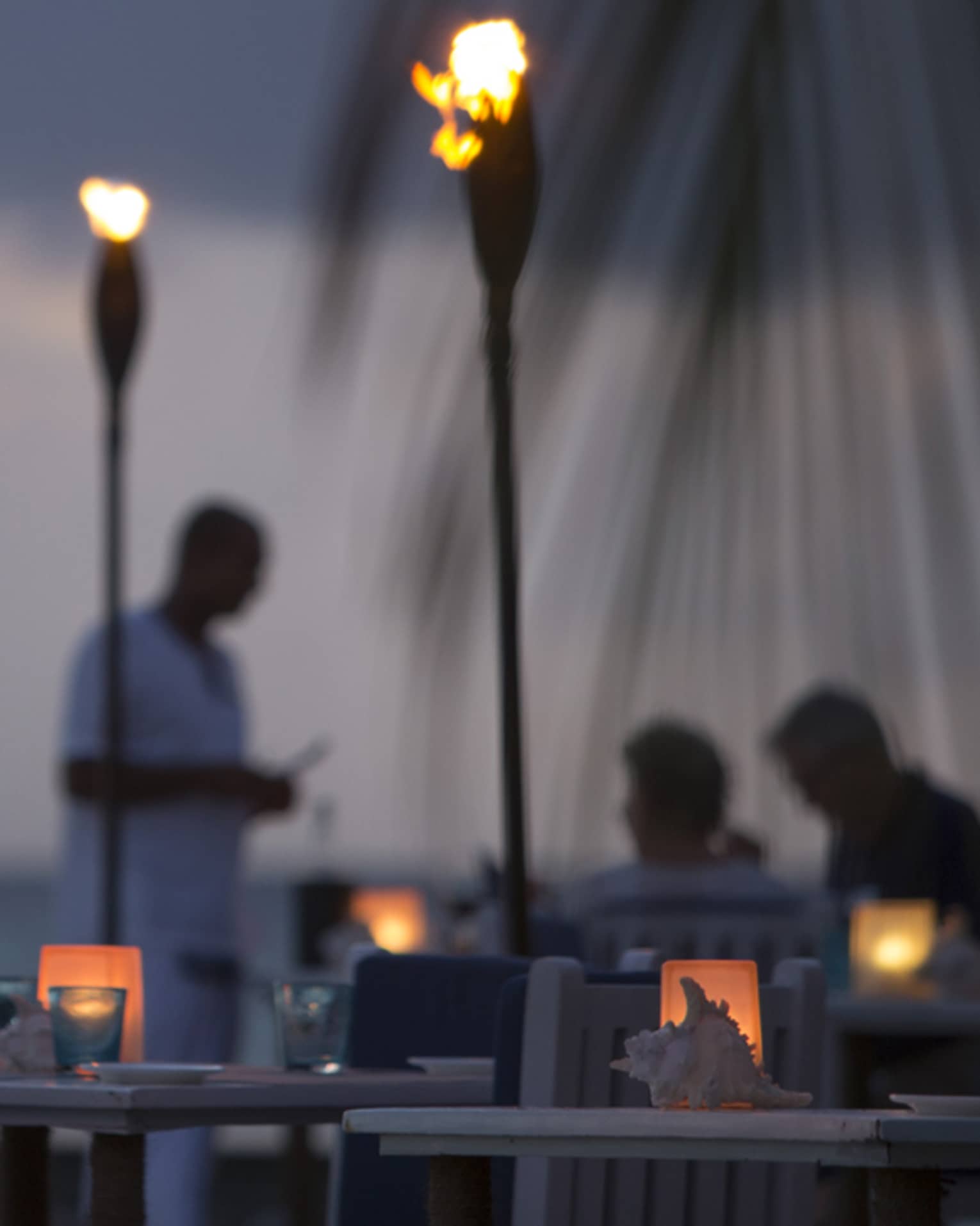Torch-lit dinner at Baraabaru, silhouettes of couple and server in background