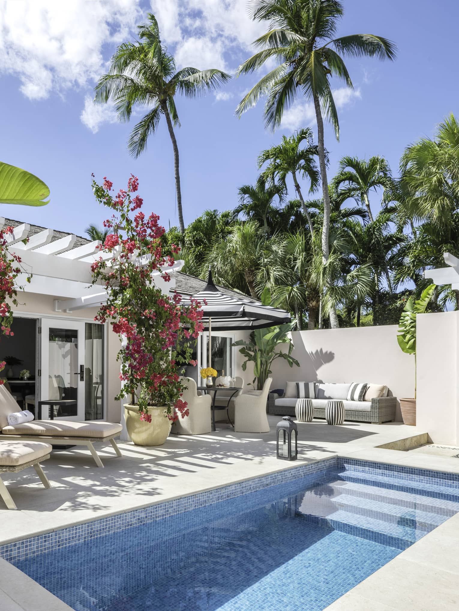 Resort bungalow with a private plunge pool, lounge chairs and lush tropical plants