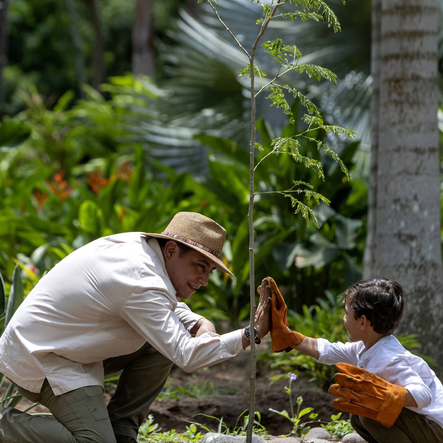Two guests giving each other a high five while wearing gloves surrounded by nature.