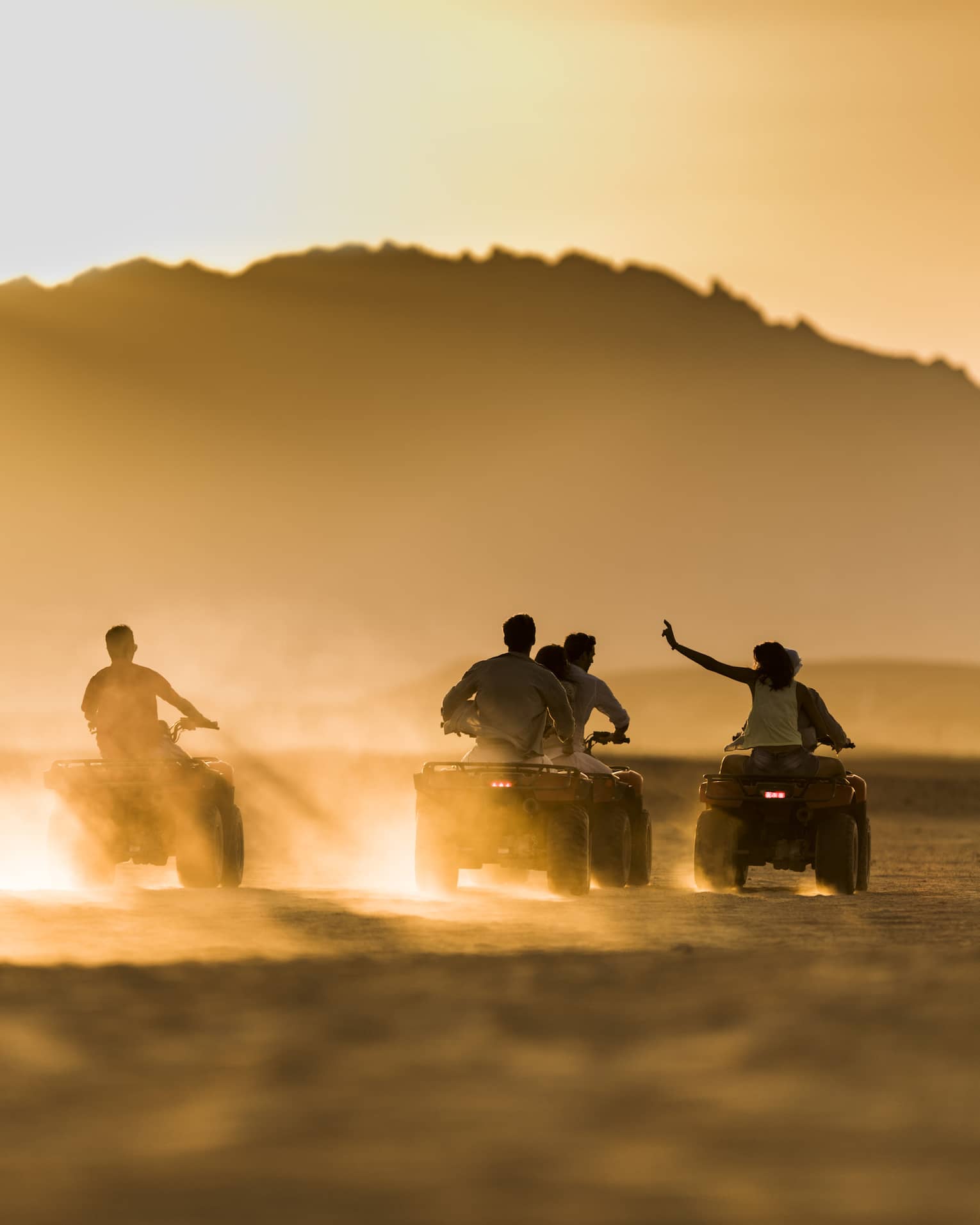 A group of people speed across the desert by e-quad