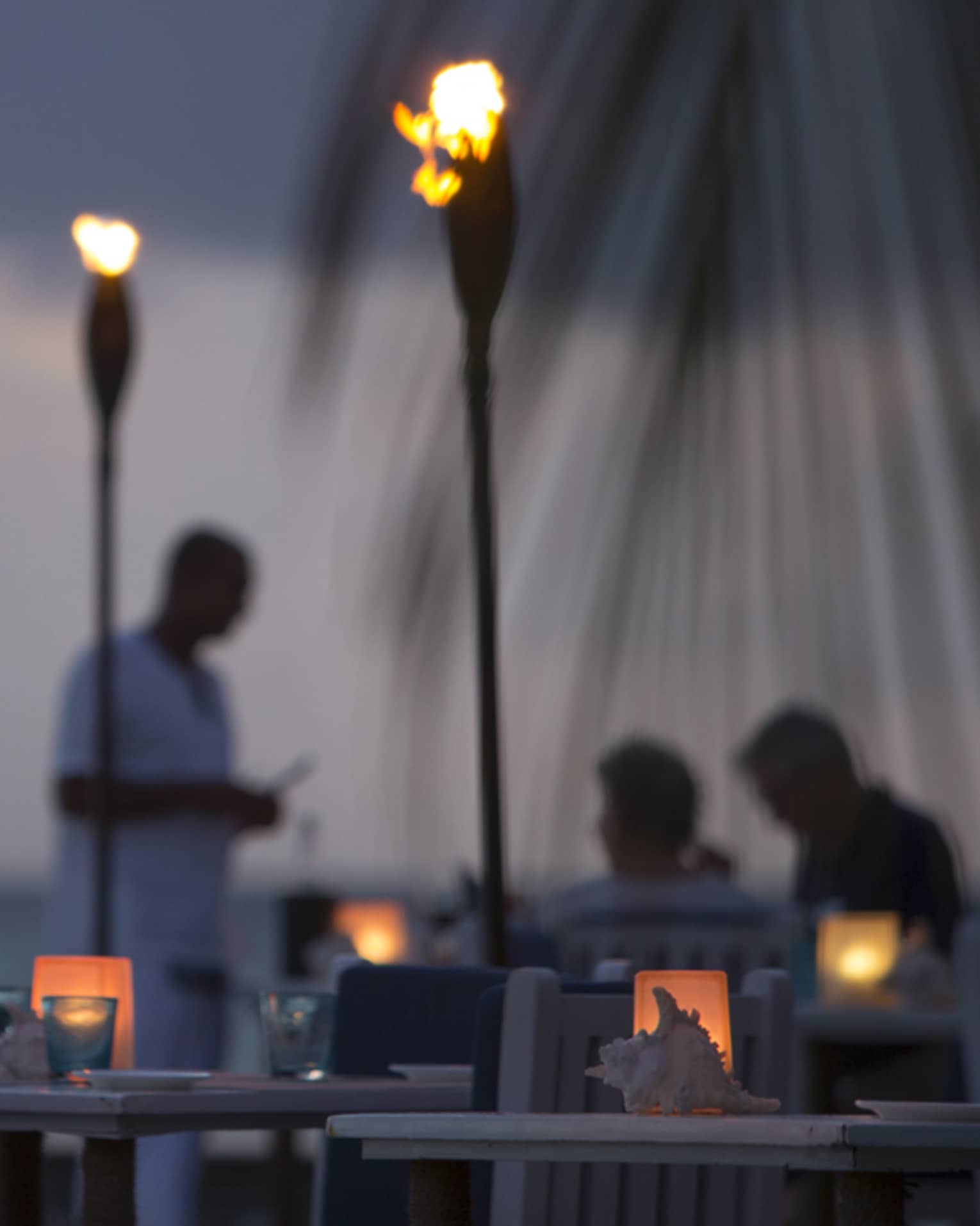 Torch-lit dinner at Baraabaru, silhouettes of couple and server in background